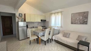 A compact kitchen with a dining area, a sofa, and a small table. - Holiday apartment with air conditioning (Peroj)
