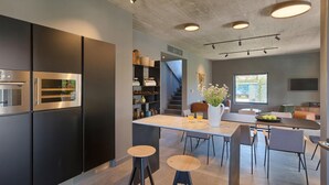 Eine moderne Küche mit eingebauten Geräten, ein Essbereich mit Barhocker und eine Treppe, die zu einem Schlafboden führt.