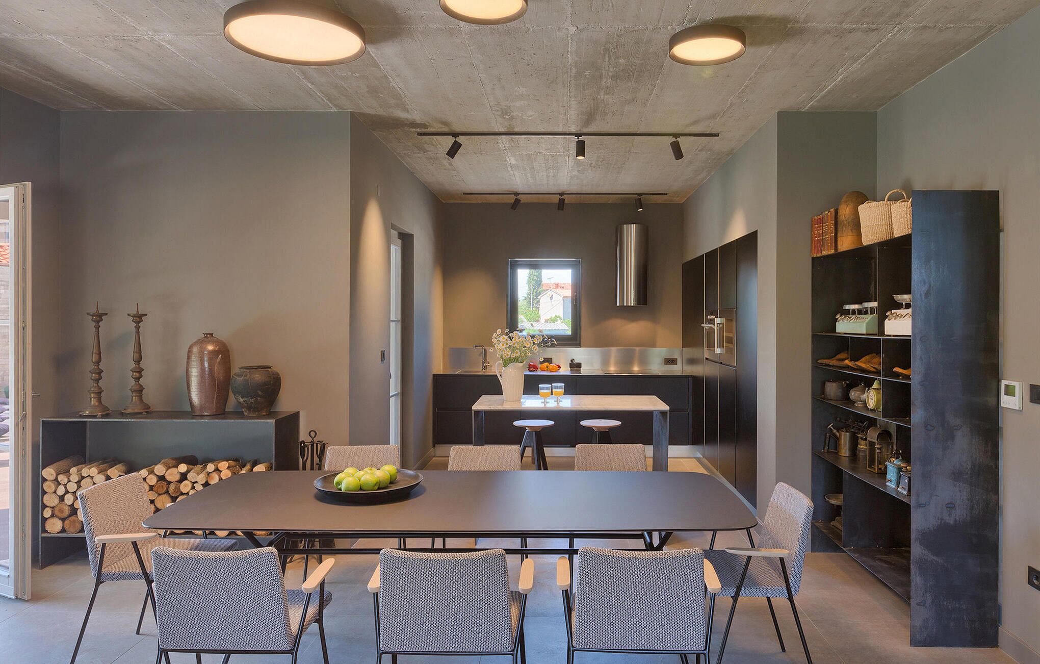 Una cocina moderna con comedor, que incluye una mesa grande, sillas y vistas al exterior a través de una ventana.