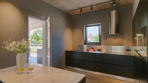 Eine moderne Küche mit Marmorarbeitsplatte, schwarzen Schränken und einem Fenster über der Spüle.
