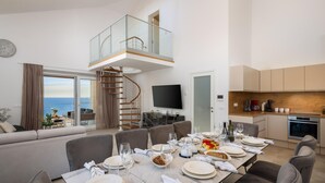 A modern living space with a dining area, a kitchen, and a balcony with a view of the sea. - Beautiful home in Rogoznica with sauna (Rogoznica)