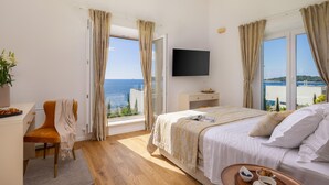 A bedroom with a bed, a desk, a chair, a TV, and a view of the sea. - Beautiful home in Rogoznica with sauna (Rogoznica)