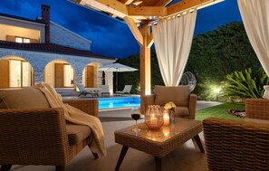 An outdoor patio with wicker furniture, a glass-top table, and a pool. - Gorgeous home in Pula (Pula)