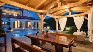 An outdoor patio with a wooden table, benches, and a pool.