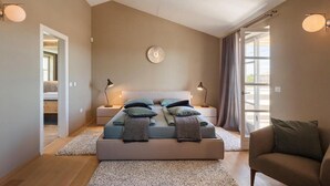 A bedroom with a bed, bedside lamps, a round wall clock, a window with curtains, and a door leading to another room. - Awesome home in Porec (Porec)