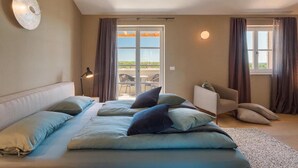 A bedroom with a large bed, a chair, a desk, and a view of the outdoors. - Awesome home in Porec (Porec)
