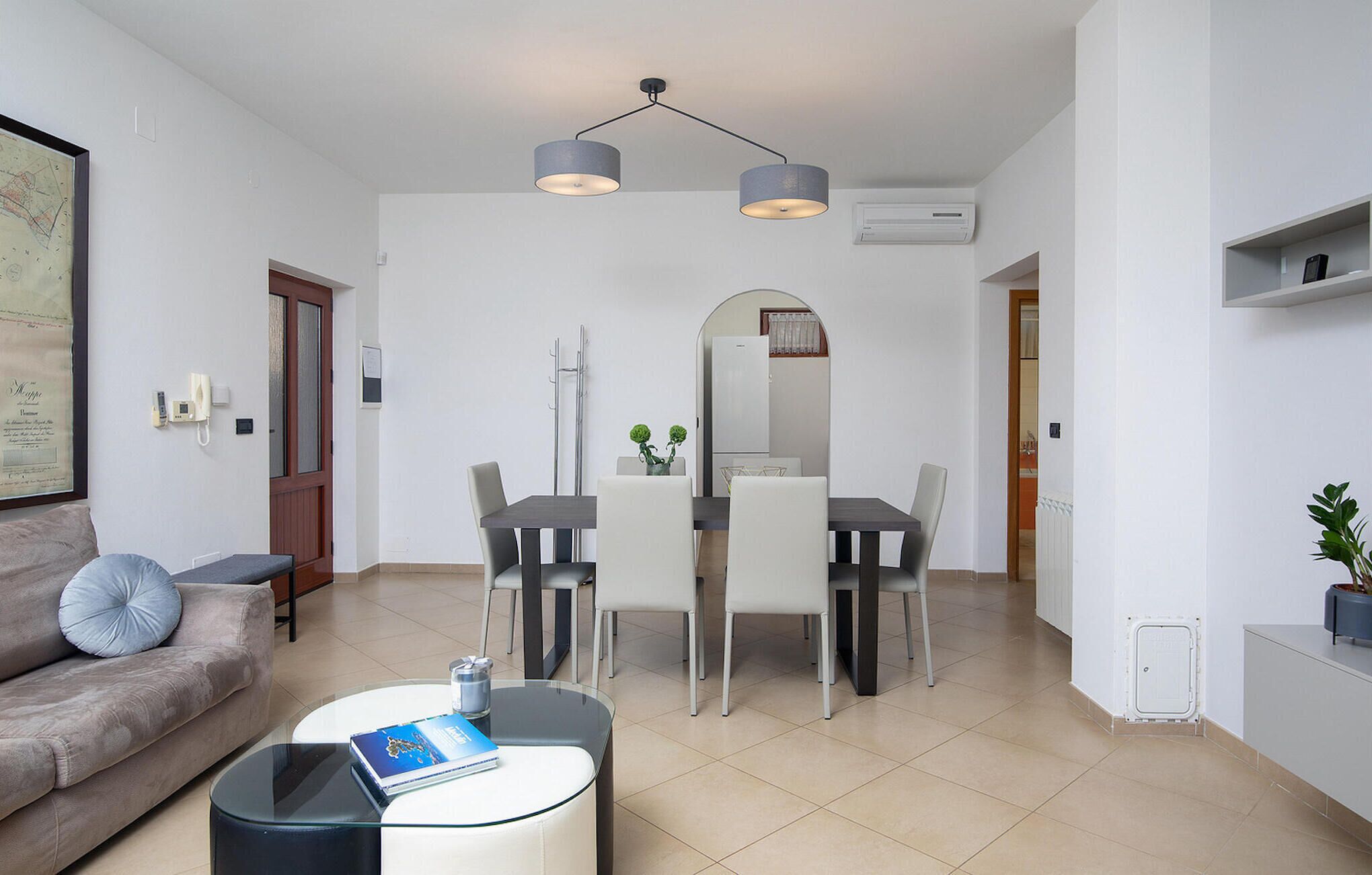 Una sala de estar moderna con un sofá, una mesa de centro de vidrio y una zona de comedor con una mesa y sillas.