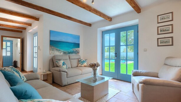 A spacious living room with a large window, a painting of a beach, and a blue door. - Pet friendly home in Pula (Pula)