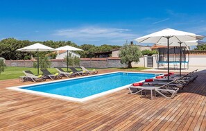 A rectangular swimming pool with a wooden deck, surrounded by lounge chairs and umbrellas. - Stunning home in Pula (Pula)