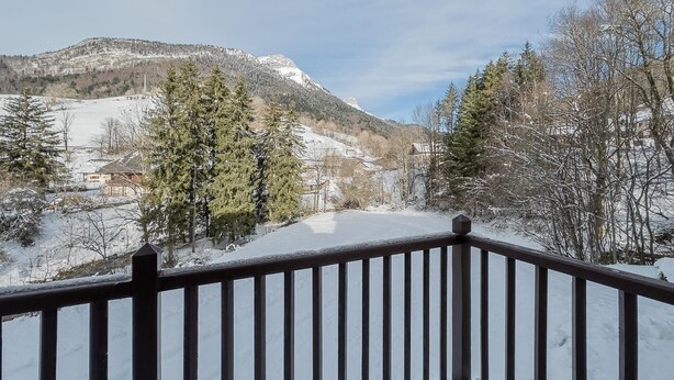 Un paysage enneigé, avec une montagne en arrière-plan et une balustrade en bois au premier plan.