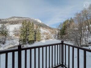 A snow-covered landscape with a mountain in the background and a wooden balcony railing in the foreground. - LE Motzon - Aillon LE Jeune (AILLON LE JEUNE)