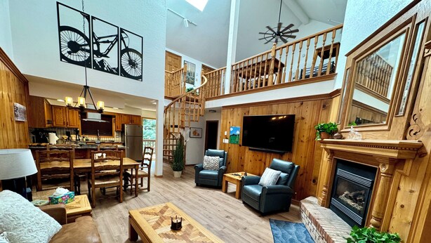 A spacious living area with a dining table, sofas, a fireplace, and a television.