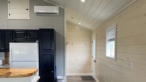 A modern kitchen with dark cabinets, a white refrigerator, and a wooden countertop. - Family friendly cottage, covered deck, close to lake to fish, swim, and boat (Whitney Point)