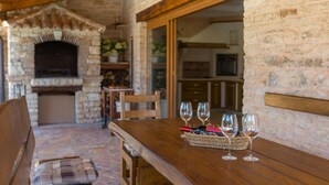 A rustic stone fireplace, wooden table with wine glasses, and a cozy seating area. - Pet friendly home in Barban (Barban)