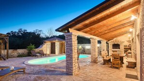 A stone pool with lounge chairs, a stone building with a fireplace, and a wooden pergola. - Pet friendly home in Barban (Barban)