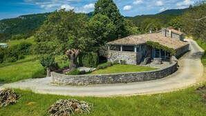 A stone house with a tiled roof, surrounded by a stone wall, set in a lush green landscape with hills in the background. - Stunning home in Buzet (Buzet)