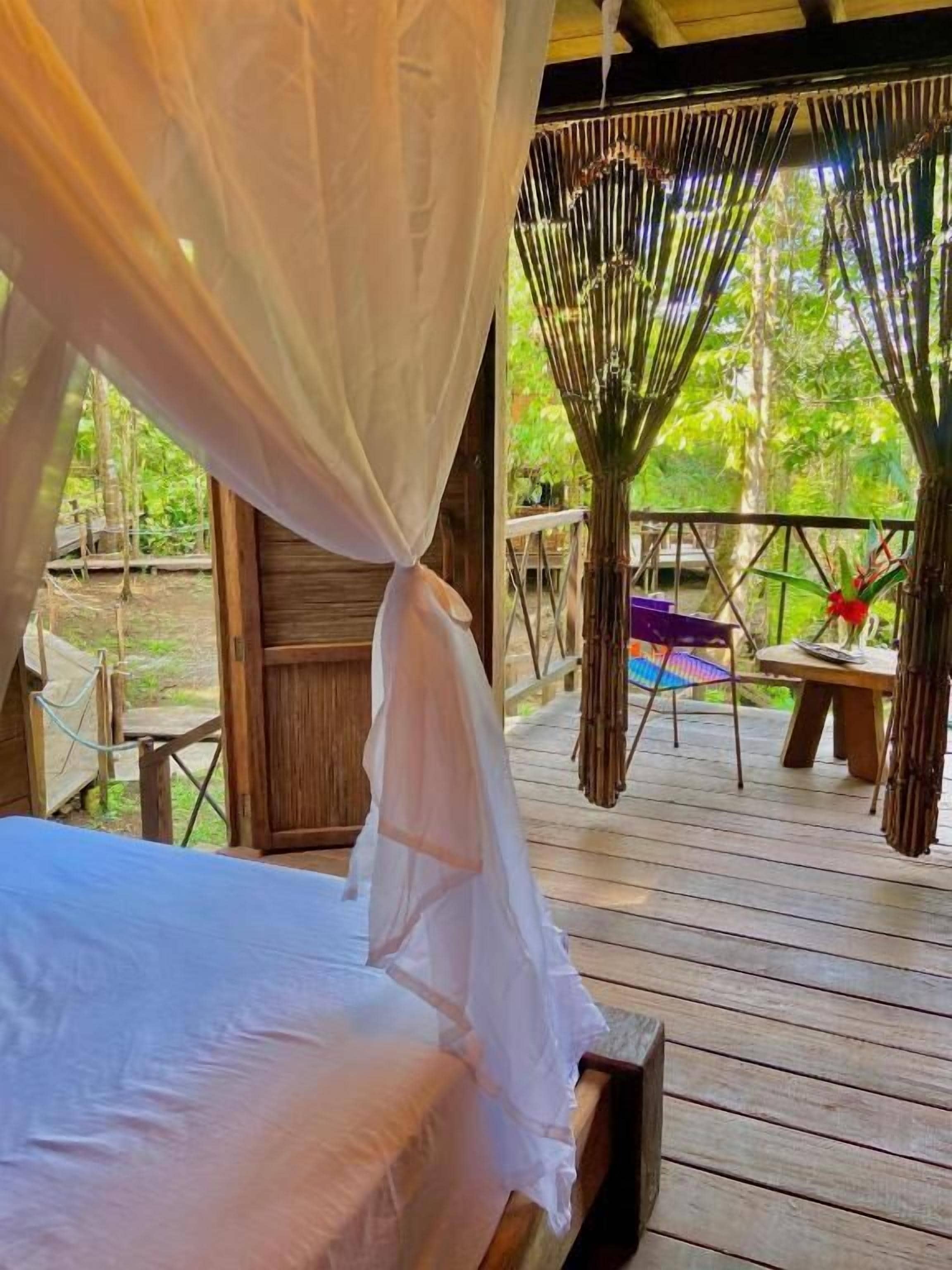 A wooden deck with a bed, a table, and chairs.