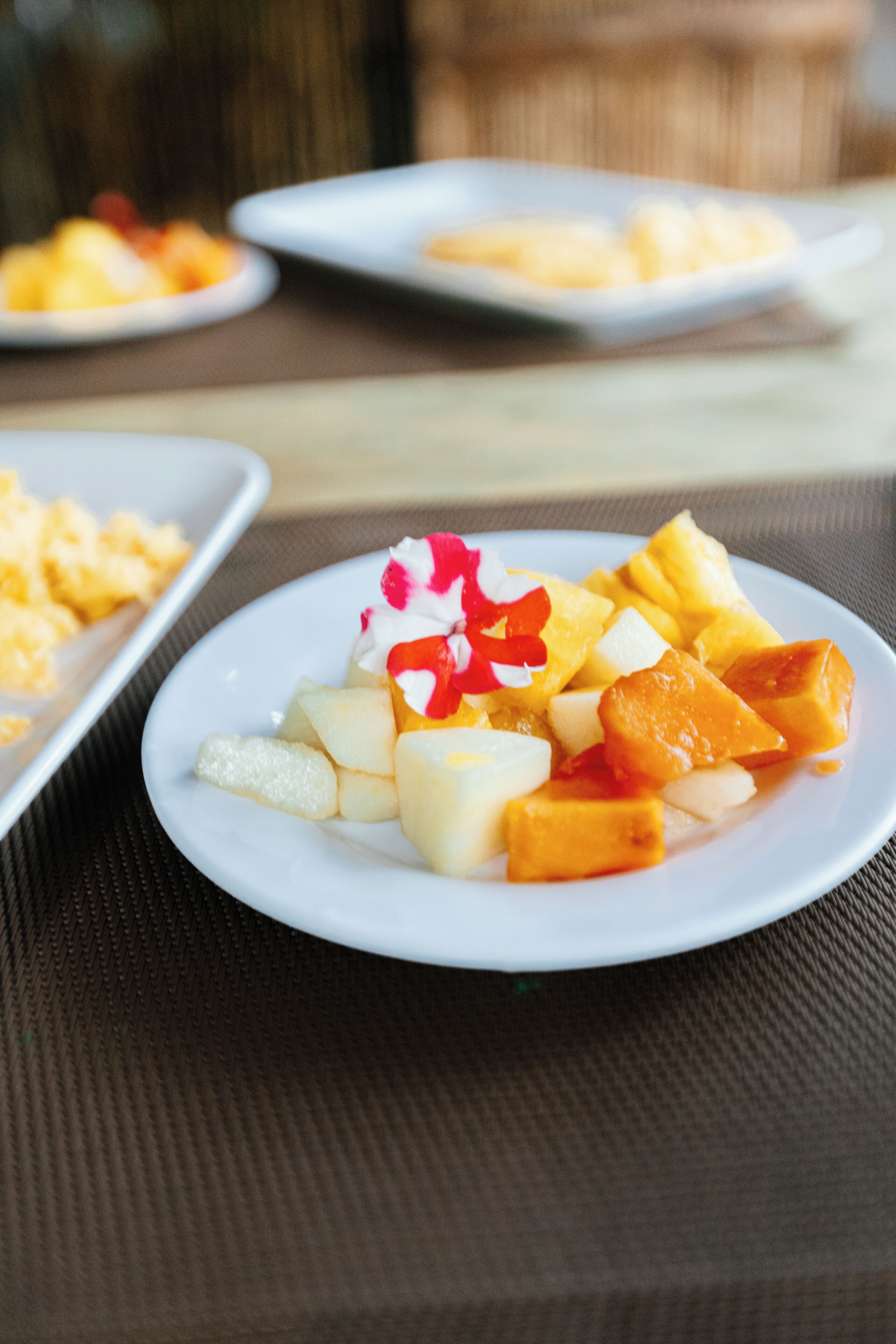A plate of fruit salad with a white plate on a textured surface.