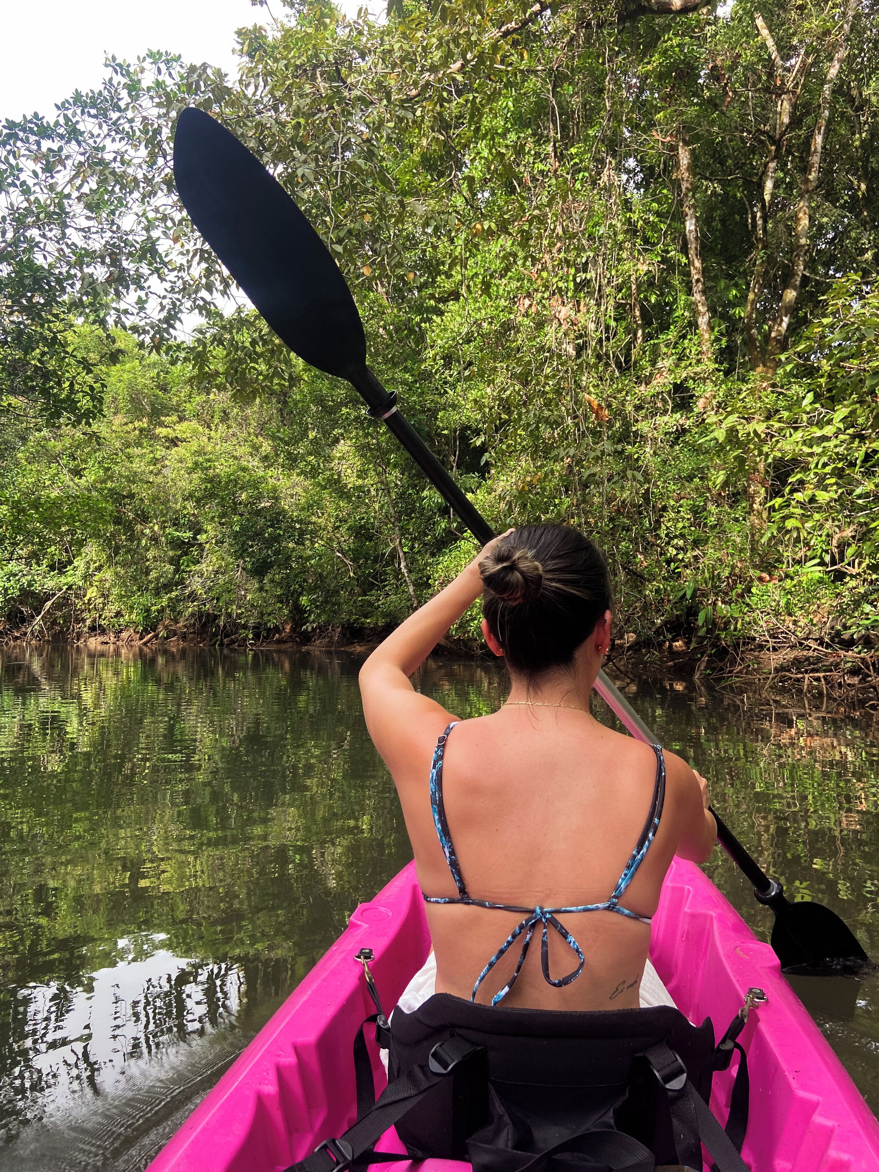 Una persona practica kayak en un río rodeado de vegetación densa.