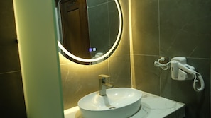 A bathroom with a round mirror, a sink, and a hairdryer on the wall. - SoursdeiSawadeeBoutique (Kampot)