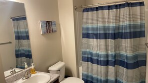 A bathroom with a white sink, a toilet, and a shower curtain with blue stripes.