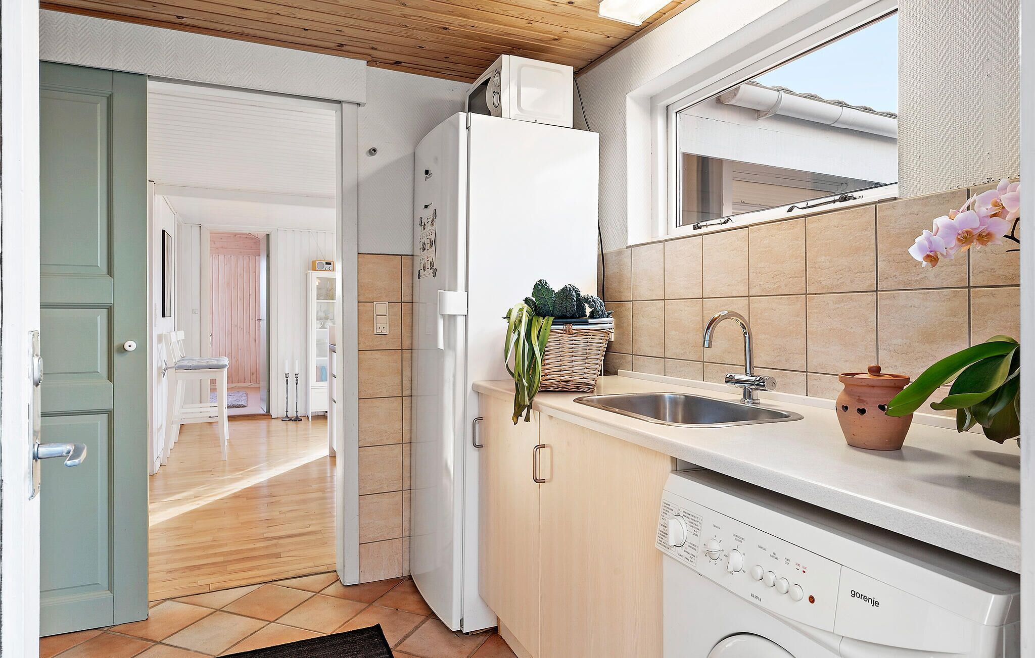 Een praktische keuken met een inbouwvaatwasser, een spoelbak en een magnetron boven de koelkast.