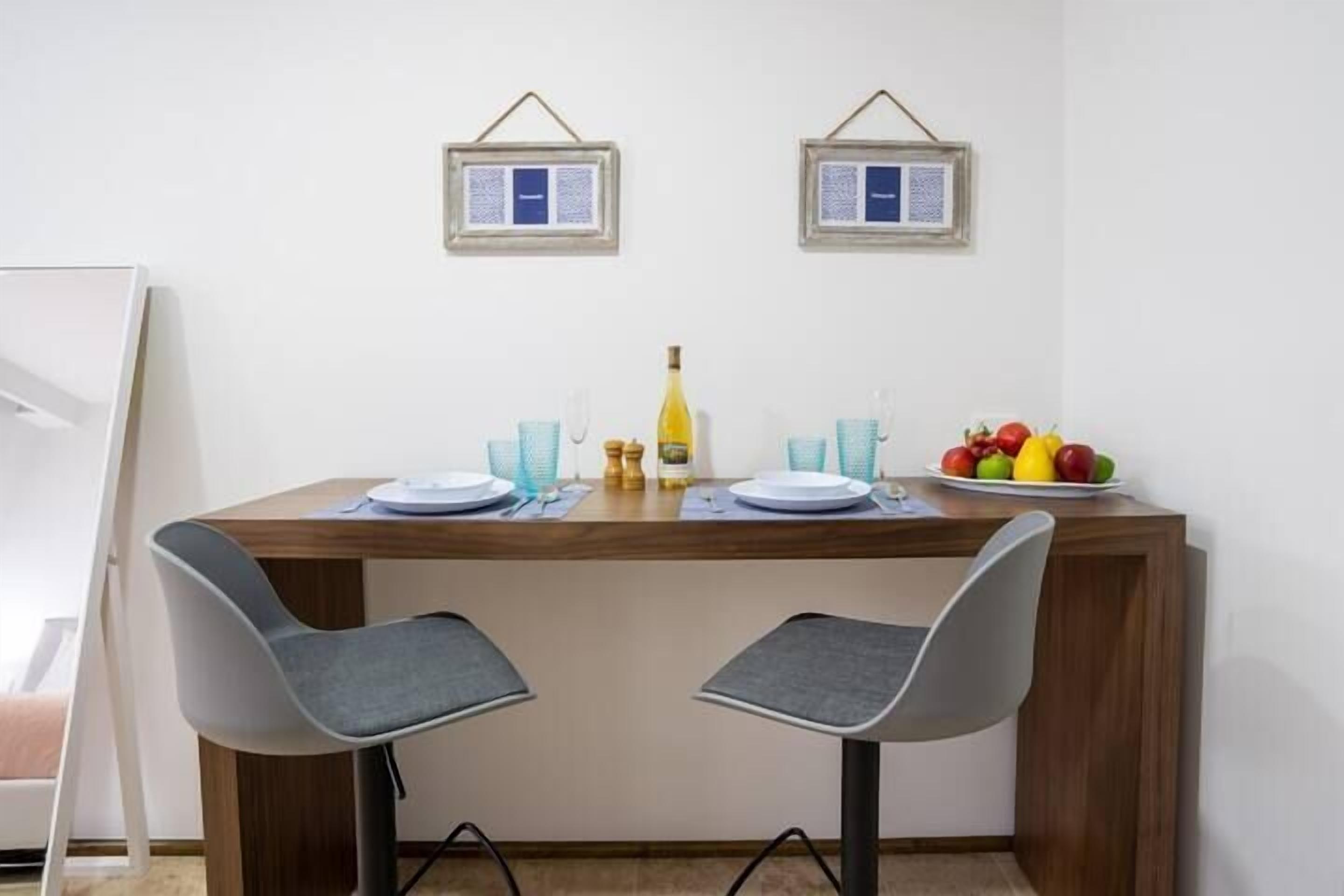A dining area with two chairs, a table, and a fruit bowl.