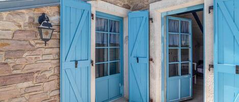 A stone building with two blue doors, each with a window.