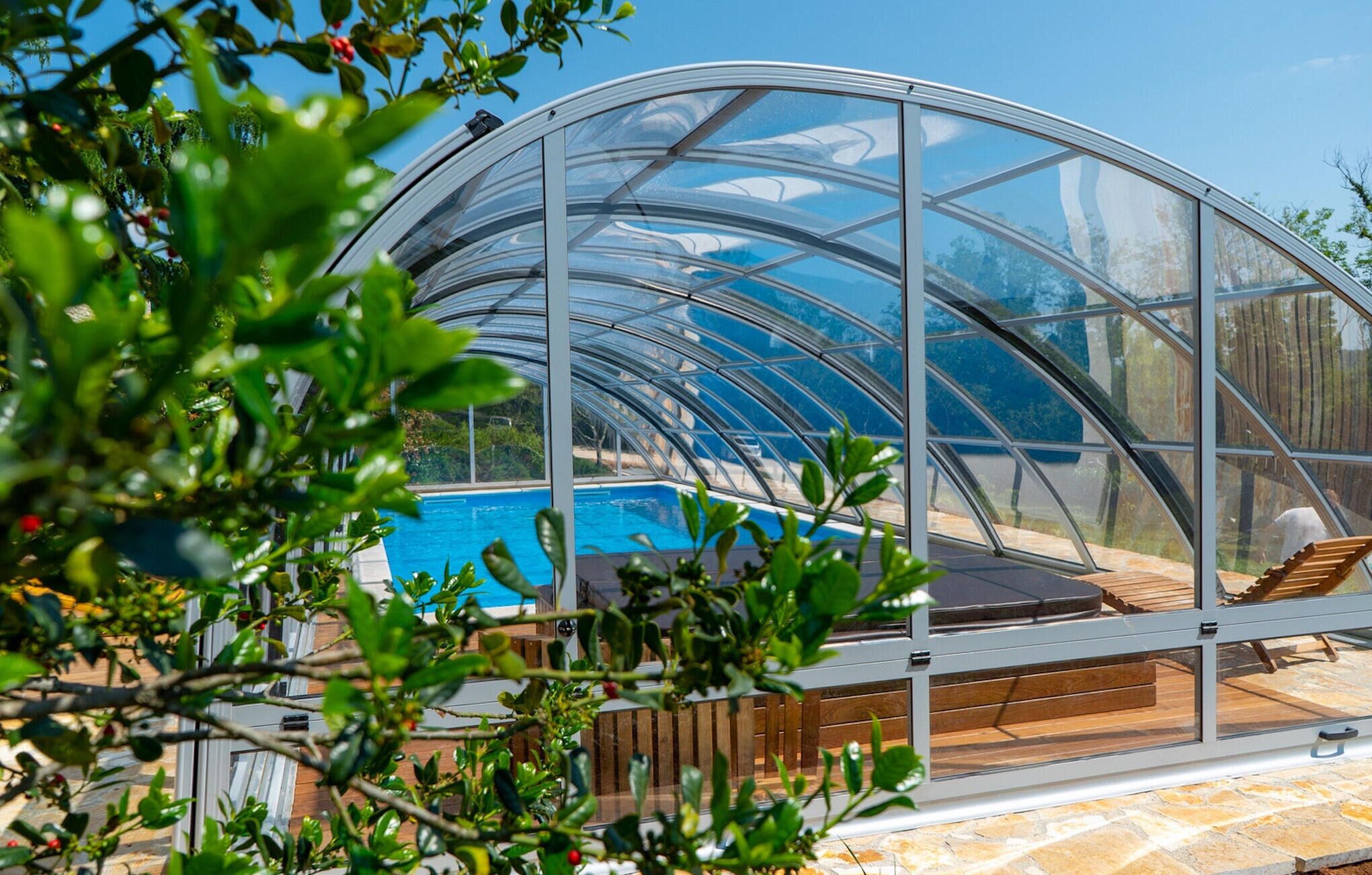 A glass-enclosed pool area with wooden decking and seating.