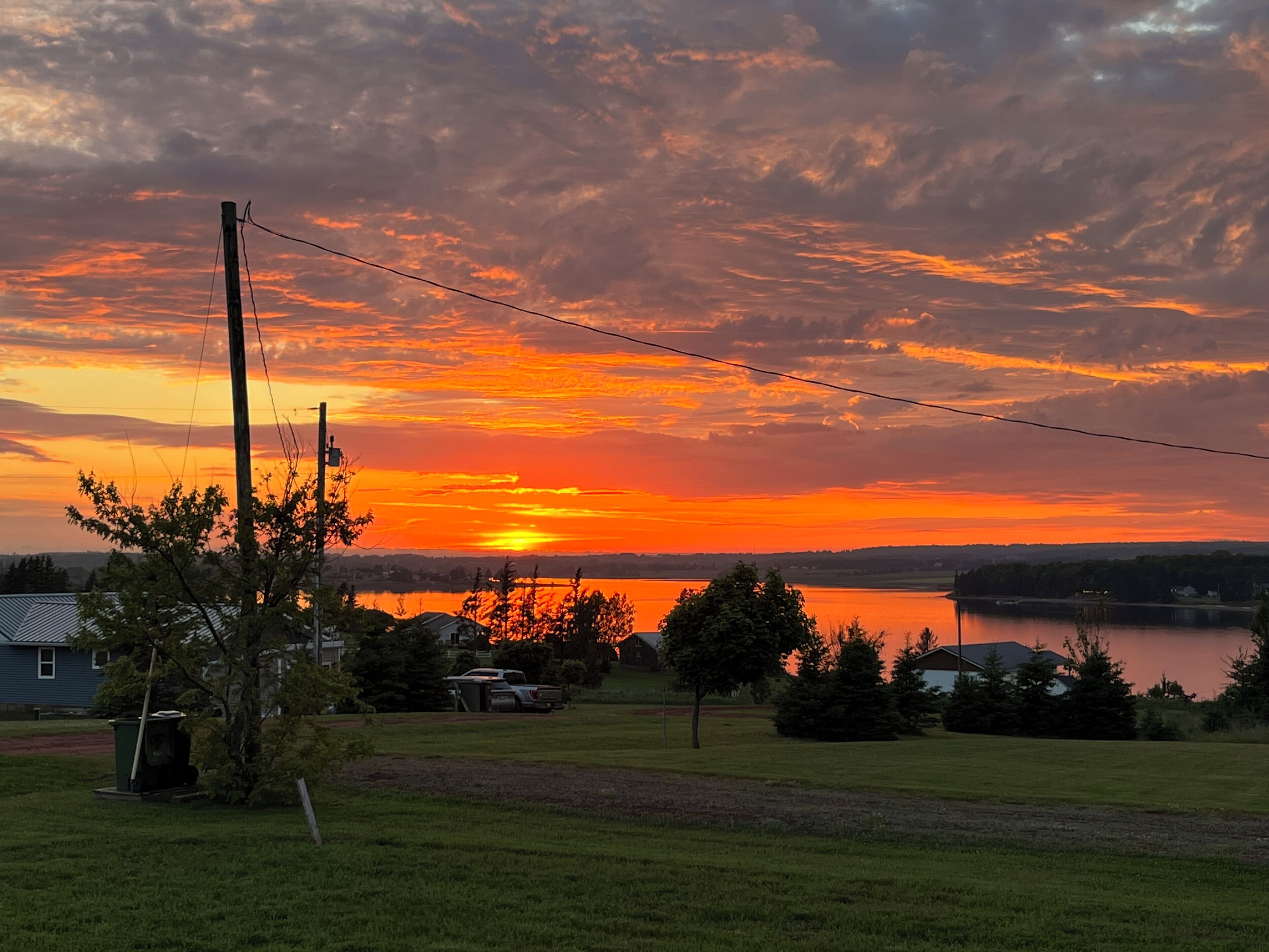 Un atardecer sobre un lago, con una zona residencial al frente.
