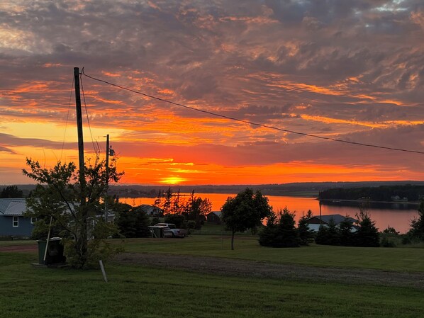 Un atardecer sobre un lago, con una zona residencial al frente.