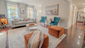 Ein modernes Wohnzimmer mit einer Couch, Sesseln, Poufs und einem Couchtisch.
