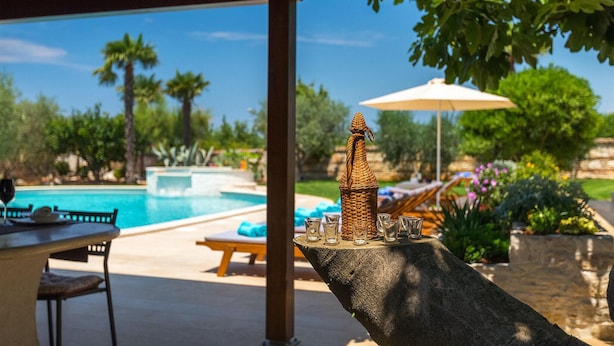 A poolside area with a tiki bar, lounge chairs, and a view of a swimming pool.