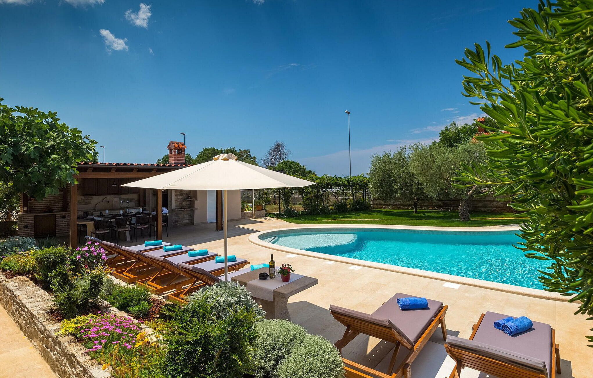 A pool area with lounge chairs, a covered seating area, and a barbecue setup.