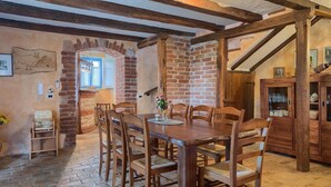 Un comedor rústico con pared de ladrillo, vigas de madera y una mesa de madera con sillas.