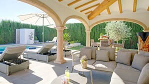 A covered outdoor seating area with lounge chairs, a pool, and a table with drinks. - Villa SanMar by Interhome (Jávea)