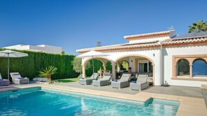A swimming pool with lounge chairs and a pergola, surrounded by a well-maintained hedge and a white building with arches. - Villa SanMar by Interhome (Jávea)