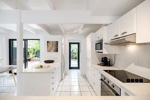 A modern kitchen with white cabinetry, a central island, and a view to the outdoors. - 'Villa One' Walk to Noosa Beach & Hastings Street (Noosa)
