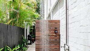 A wooden shower enclosure with a rain showerhead, a metal faucet, and a bottle of shampoo on a shelf. - 'Villa One' Walk to Noosa Beach & Hastings Street (Noosa)