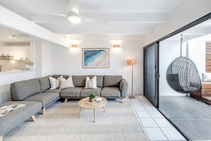 A modern living room with a grey sectional sofa, a round coffee table, and a hanging chair. - 'Villa One' Walk to Noosa Beach & Hastings Street (Noosa)