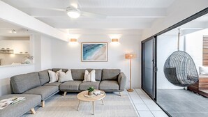 A modern living room with a sectional sofa, a round coffee table, and a hanging chair. - 'Villa One' Walk to Noosa Beach & Hastings Street (Noosa)