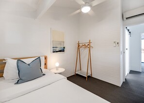 A hotel room with a bed, a bedside table with a lamp, a wooden hanger, and a door leading to another room. - 'Villa One' Walk to Noosa Beach & Hastings Street (Noosa)