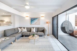A modern living room with a sectional sofa, a round coffee table, and a hanging chair. - 'Villa One' Walk to Noosa Beach & Hastings Street (Noosa)