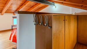 Une pièce avec des poutres apparentes en bois au plafond, une armoire avec un miroir et un porte-manteau mural.