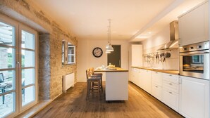 A modern kitchen with a stone wall, wooden flooring, and white cabinetry. - Beautiful home in Buje (Buje)