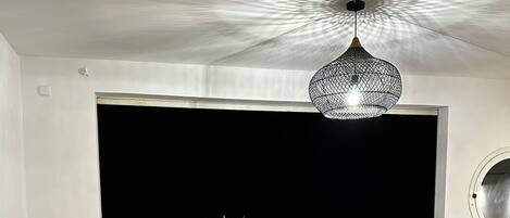A dining area with a round wooden table, chairs, a hanging light fixture, and a dog lying on the floor.
