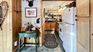 Une cuisine rustique avec des meubles en bois, une table verte, un tableau encadré, une décoration représentant une tête d’élan et une enseigne sur laquelle on peut lire « MOOSHEAD ».