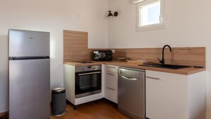 Eine kompakte Küche mit Kühlschrank, Mikrowelle, Backofen, Geschirrspüler und Spüle.