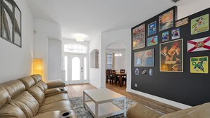 A living room with a leather couch, a white coffee table, and a wall decorated with movie posters. - Disney Family Villa w/screened-in patio, pool and spa. Peaceful golf community. (Davenport)