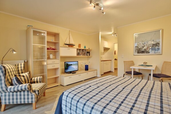 A bedroom with a bed, a TV, a desk, and a chair.